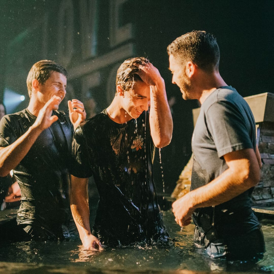 Church baptism celebration with believers standing in water during a baptism service.